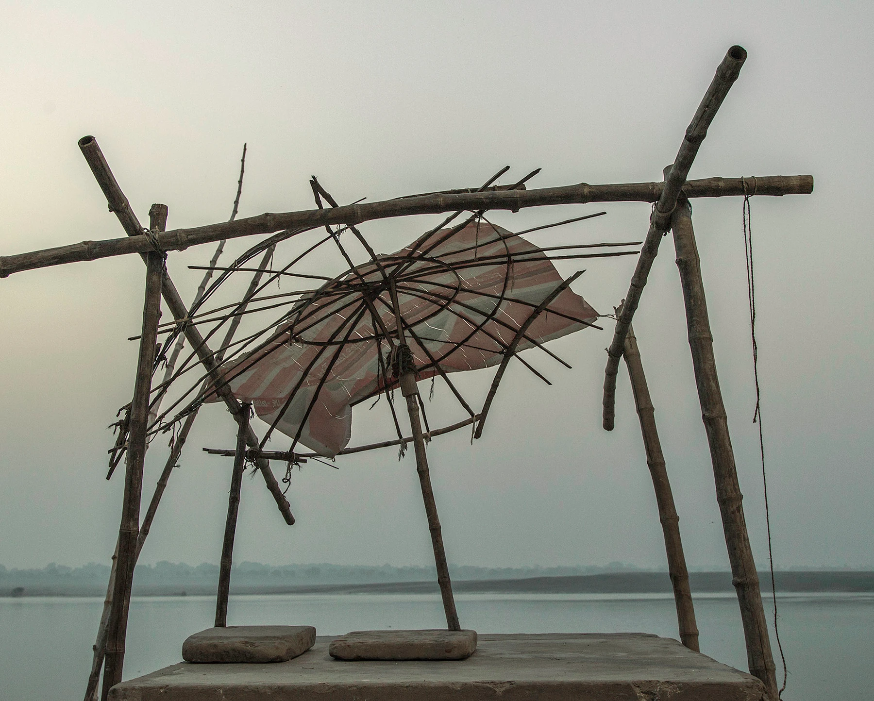 Hombres sentados bajo paraguas desvencijada junto al río Ganges en la niebla matinal — Moshka, Cristina Riesgo
